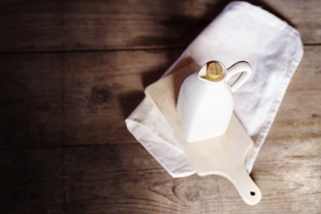 Olive oil in ceramic jug on a wooden tableの写真素材