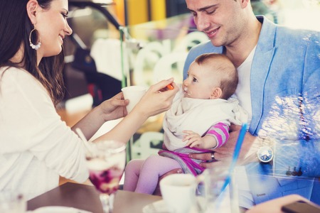 Young parents with their cute baby daughter in cafe