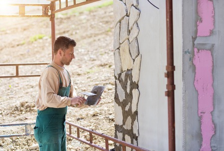 Mason putting decorative natural stones on a wallの写真素材