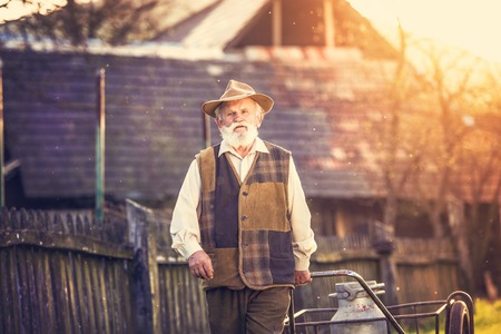Senior farmer carrying kettle full of milkの写真素材