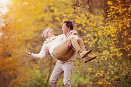 Active seniors having fun and playing with the leaves in autumn forestの写真素材