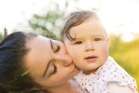 Happy mother and her baby having fun outside in spring natureの写真素材