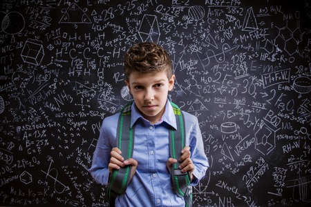Young handsome boy with school bag in front of big blackboardの写真素材