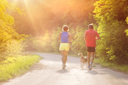 Active seniors running with their dog outside in green nature