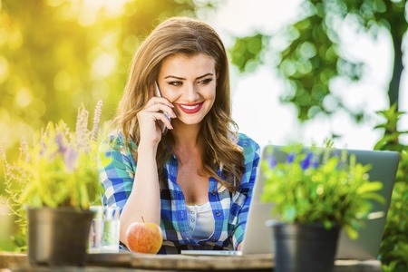 Beautiful young garden manager with a smartphone working outsideの写真素材