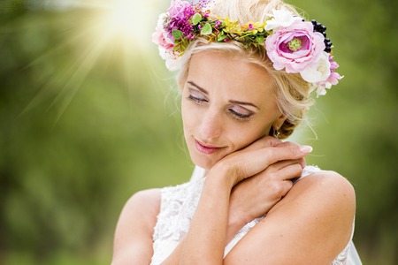 Beautiful young bride with flower wreath outside in natureの写真素材