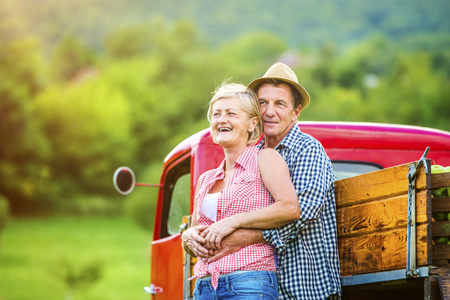 Senior couple standing next to the red truckの写真素材
