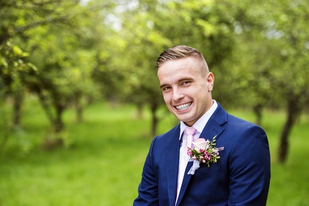 Handsome young groom posing outside in natureの写真素材