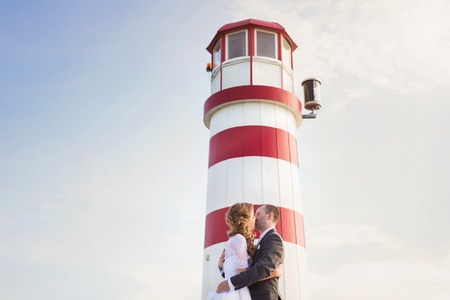 Beautiful young wedding couple in front of lighthouseの写真素材