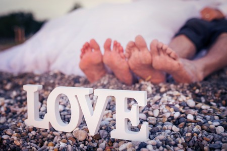 Feet of a bride and groom sitting on a beach