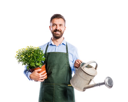 Young handsome gardener in green apron. Studio shot on white backgroundの写真素材