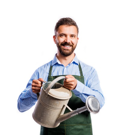 Young handsome gardener in green apron. Studio shot on white backgroundの写真素材