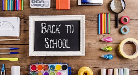Desk with stationary and with Back to school sign. Studio shot on wooden background.