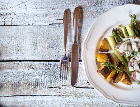 Food on a plate, fork and knife on a wooden background.の写真素材