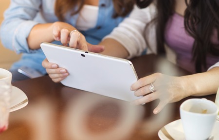 Two beautiful women with tablet in cafeの写真素材