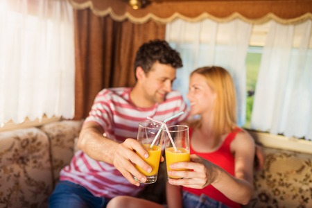 Beautiful young couple sitting in a camper van on a summer dayの写真素材