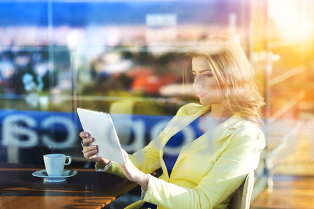 Double exposure of an attractive young woman with tablet in a cafeの写真素材
