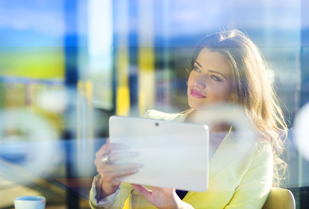 Double exposure of an attractive young woman with tablet in a cafeの写真素材