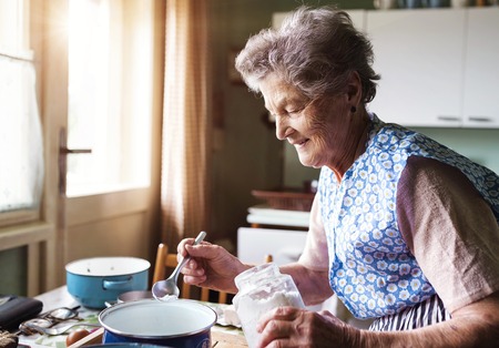 Senior woman baking pies in her home kitchen.  Measuring ingredients.の写真素材
