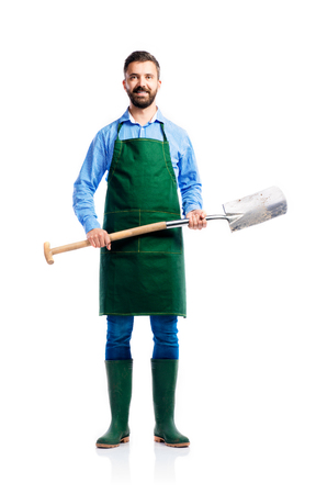 Young handsome gardener in green apron. Studio shot on white backgroundの写真素材
