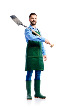 Young handsome gardener in green apron. Studio shot on white backgroundの写真素材
