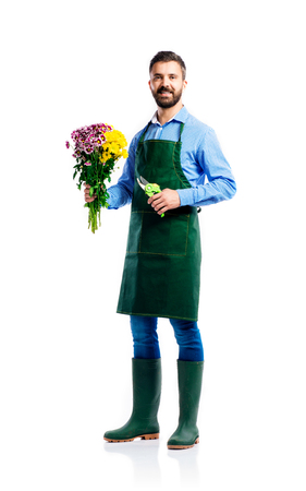 Young handsome gardener in green apron. Studio shot on white backgroundの写真素材
