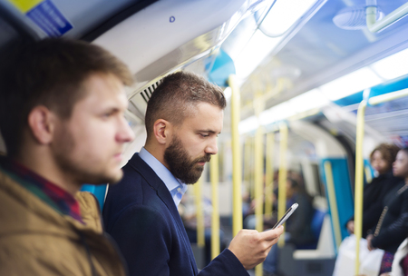 Young handsome businessman with smartphone in subway