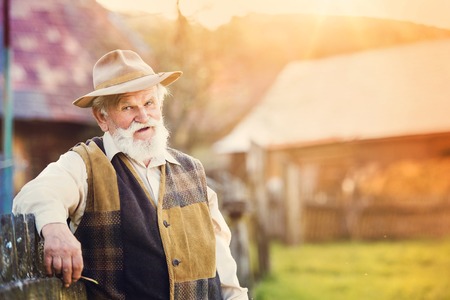 Senior man standing outside at the wooden fenceの写真素材