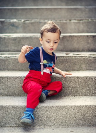 Cute little boy sitting on stairs during a summer dayの写真素材
