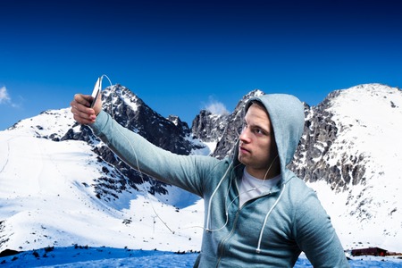 Young runner taking selfie in sunny winter mountainsの写真素材