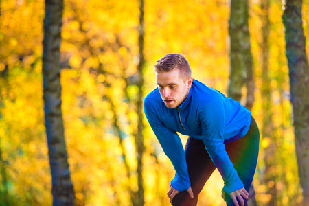 Young handsome runner outside in sunny autumn natureの写真素材
