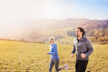 Beautiful couple running outside in autumn natureの写真素材