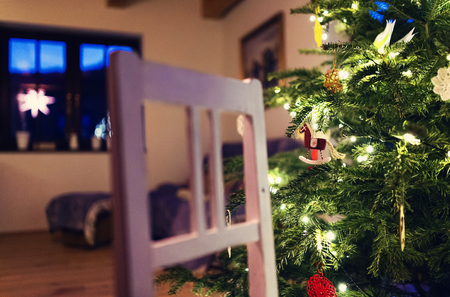 Close up of decorated Christmas tree and white wooden chairの写真素材