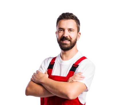 Young handsome worker in red overalls. Studio shot on white backgroundの写真素材
