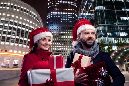 Young beautiful couple with Santa hats in the city