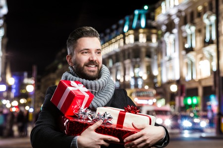 Young handsome man with Christmas presents in the cityの写真素材