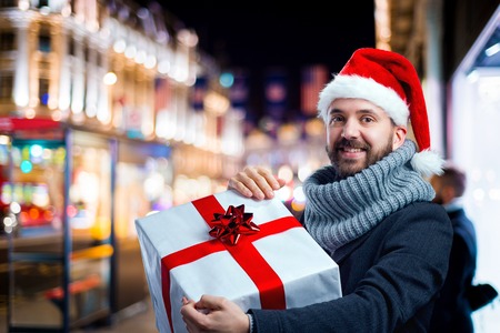 Young handsome man with Christmas present in the cityの写真素材