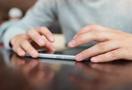 Handsome young man with smartphone sitting in a cafeの写真素材