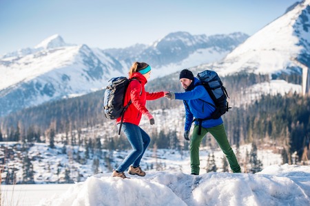 Young couple hiking outside in sunny winter mountainsの写真素材