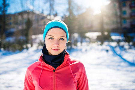 Young woman jogging outside in sunny winter mountainsの写真素材