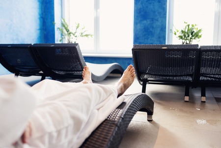 Man in  white bathrobe sitting in lounge chair in spa roomの写真素材