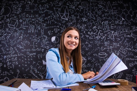 Beautiful student doing her homework in front of big blackboardの写真素材