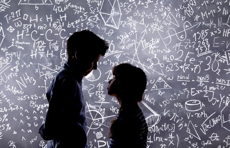 Cute little boy and girl in front of a big blackboard. Studio shot on black background.の写真素材