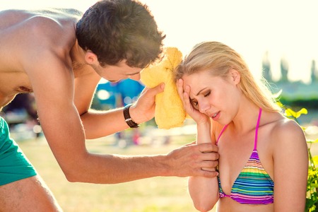 Young woman with heatstroke on a beachの写真素材