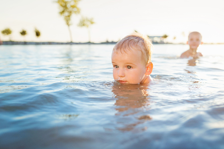Cute little blond boys swimming in the water on sunny summer dayの写真素材
