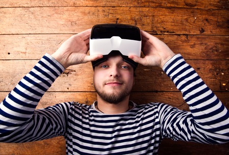 Man wearing virtual reality goggles. Flat lay. Studio shot, wooden background