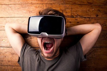 Close up of a man wearing virtual reality goggles. Facial expression, screaming. Flat lay. Studio...