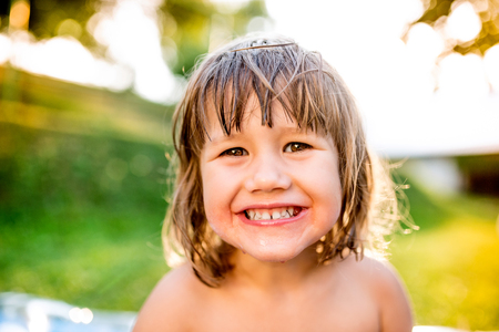 Cute little smiling girl having fun in sunny summer garden,の写真素材