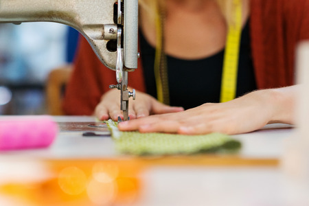 Close up of hands of unrecognizable tailor woman working with old sewing machine