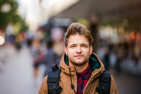 Close up of young hipster man in brown winter jacket walking in the streets of London
